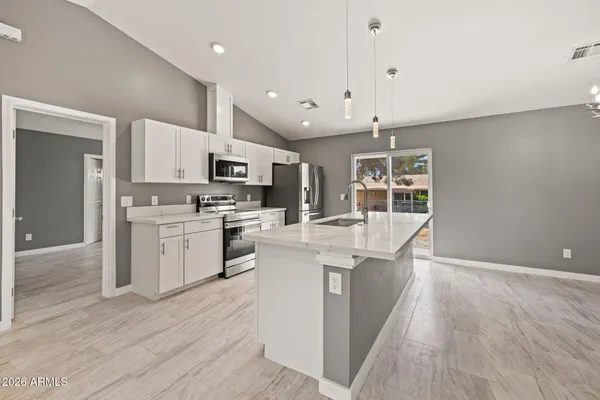 a large kitchen with stainless steel appliances kitchen island a large counter top and wooden floors