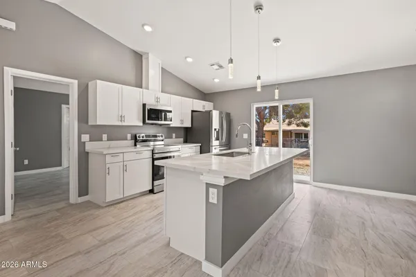 a large kitchen with stainless steel appliances kitchen island granite countertop a stove a sink and a white refrigerator