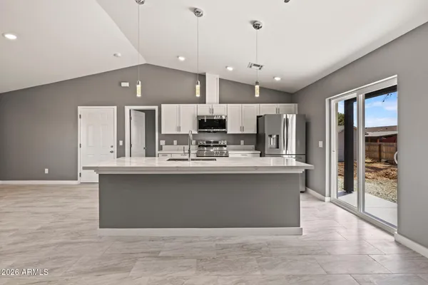 a large kitchen with stainless steel appliances a large counter top a stove and a refrigerator