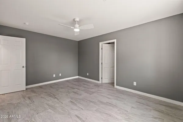 an empty room with closet and a ceiling fan