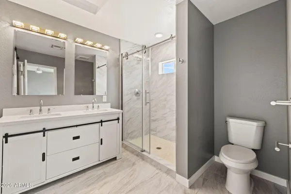 a bathroom with a toilet a sink a glass door a shower a mirror and vanity
