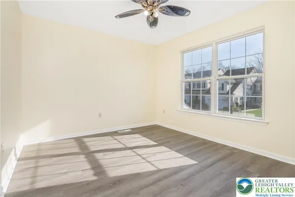 an empty room with wooden floor fan and windows