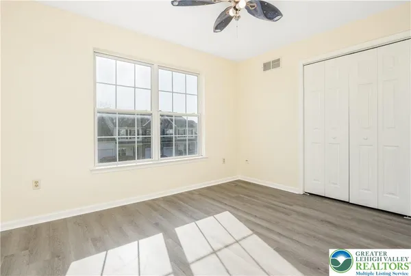 an empty room with wooden floor fan and windows