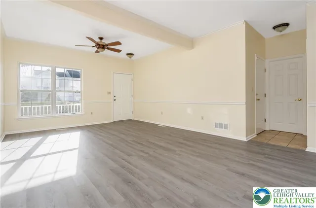 a view of an empty room with a window and wooden floor