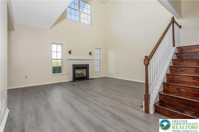 a view of an empty room with wooden floor fireplace and a window