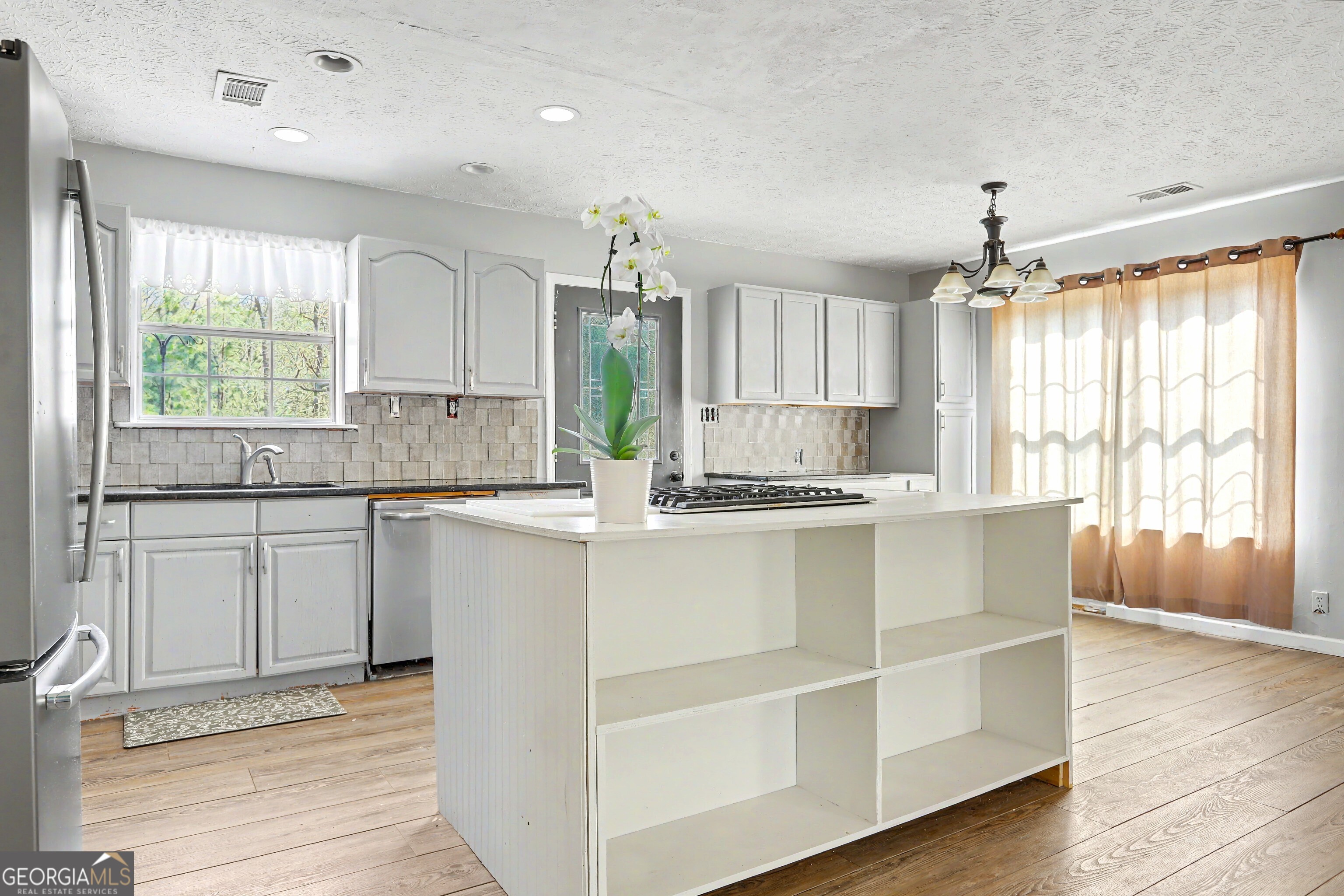 376 Doe Lane Mansfield, GA 30055 - Photo 10 of 28 a kitchen with kitchen island granite countertop a stove a sink and white cabinets with wooden floor