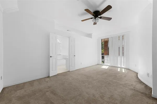 an empty room that has a ceiling fan and a window