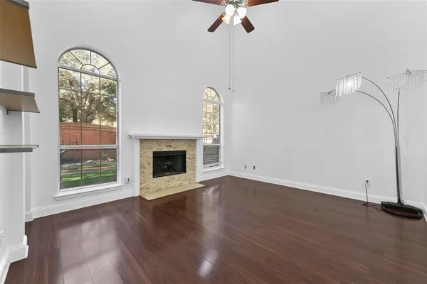 an empty room with wooden floor fan and windows
