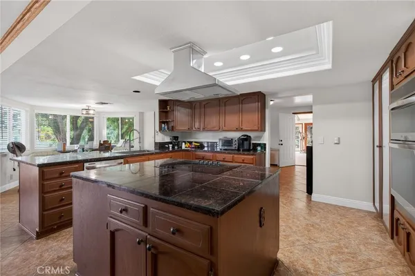 a kitchen with kitchen island granite countertop a sink a counter top space and stainless steel appliances