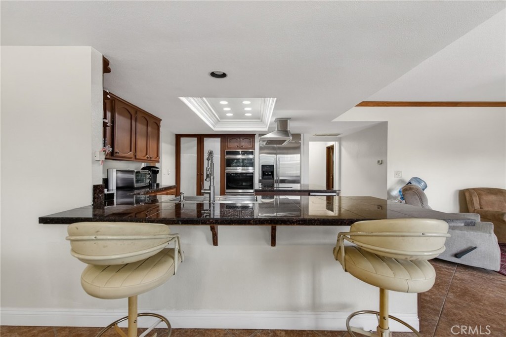 14435 Wood Road Riverside, CA 92508 - Photo 13 of 66 a living room with stainless steel appliances kitchen island granite countertop a dining table and chairs with wooden floor