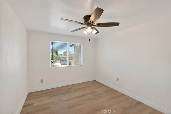 an empty room with wooden floor fan and windows