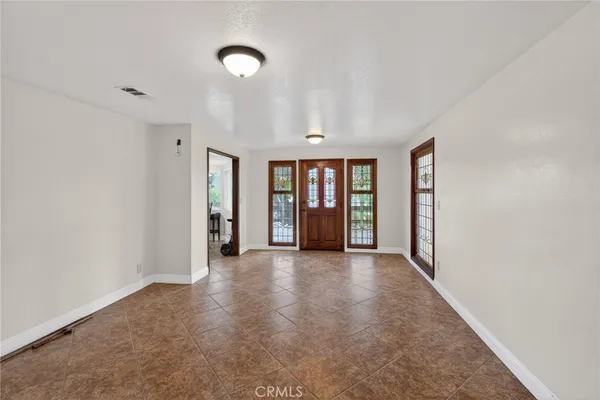 a view of an empty room with window and a kitchen