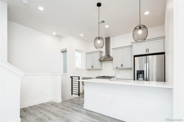 a kitchen with stainless steel appliances granite countertop a sink a refrigerator a center island a stove and a wooden floors