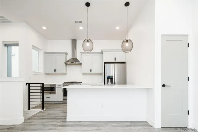 a kitchen with a refrigerator a stove and white cabinets