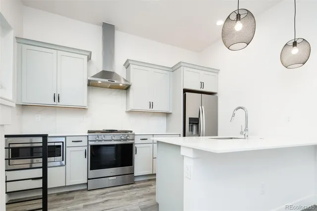 a kitchen with stainless steel appliances granite countertop a stove a sink and white cabinets