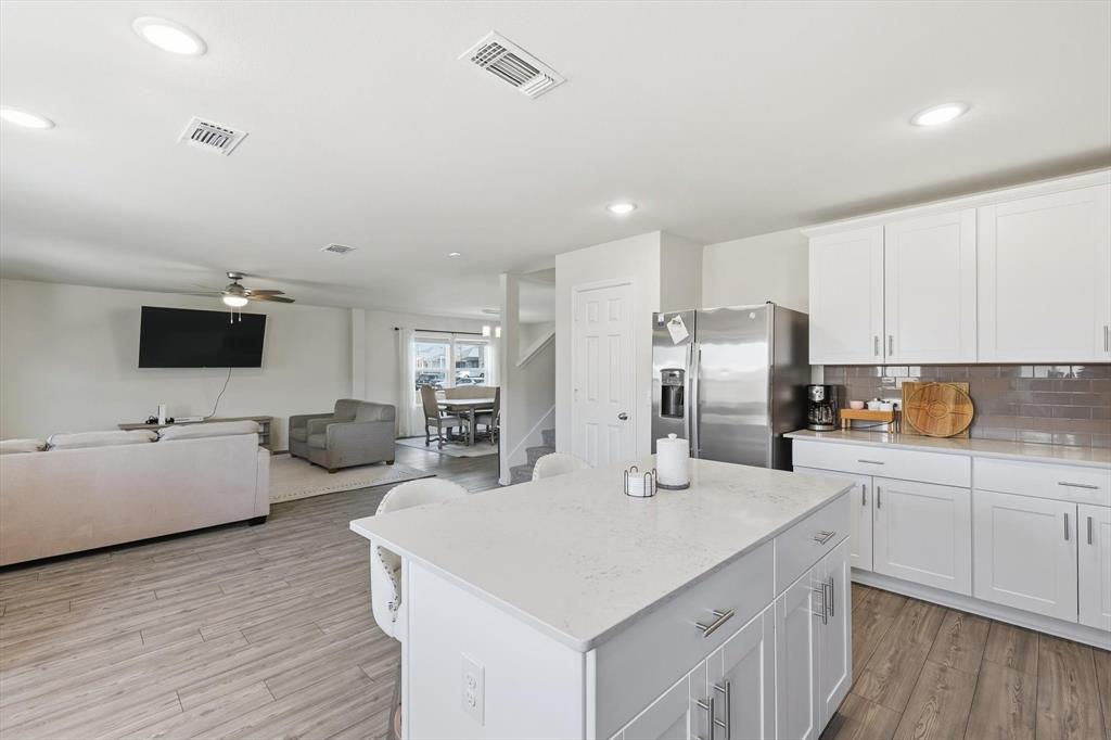 16041 Pious Drive Haslet, TX 76052 - Photo 36 of 36 Kitchen with white cabinetry, a kitchen island, stainless steel refrigerator with ice dispenser, backsplash, and open floor plan