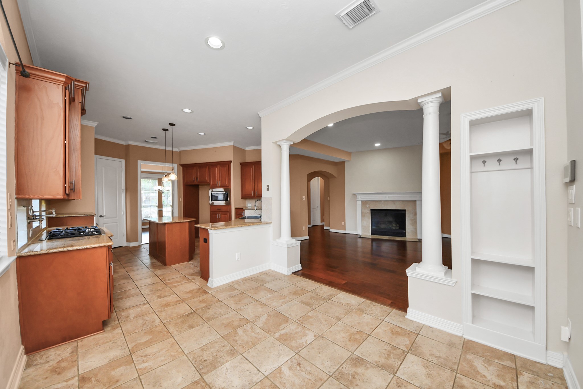 17618 Raven Canyon Lane Houston, TX 77095 - Photo 11 of 45 Spacious kitchen with ample cabinet storage, granite countertops, and an open layout to the cozy living room featuring a built-in fireplace and archways. Perfect for entertaining!