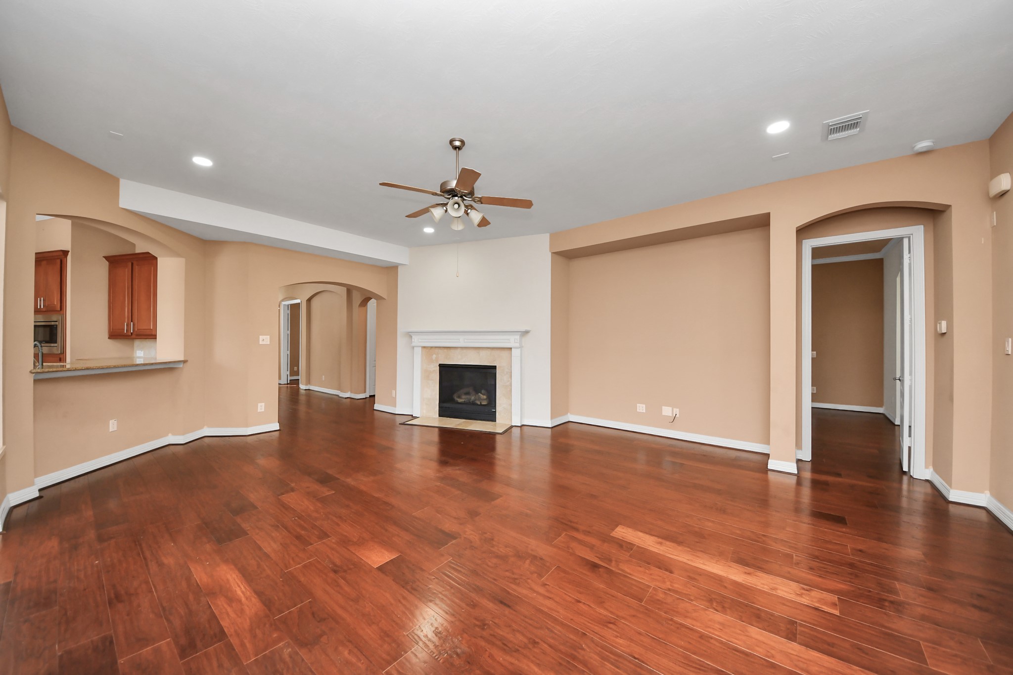 17618 Raven Canyon Lane Houston, TX 77095 - Photo 13 of 45 A welcoming living area with a gas fireplace, ceiling fan, and large windows letting in plenty of natural light, perfect for entertaining or relaxing.