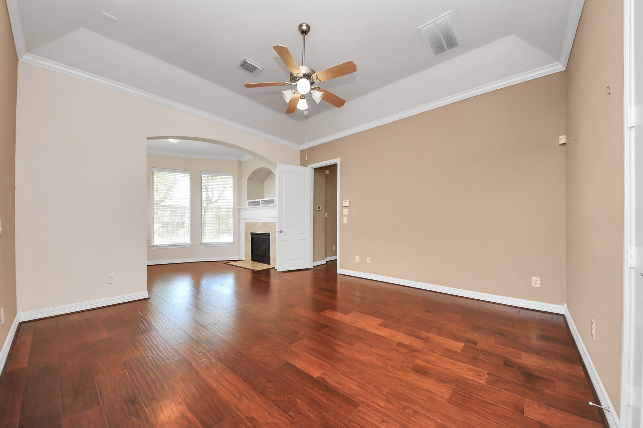 17618 Raven Canyon Lane Houston, TX 77095 - Photo 14 of 45 Bright and inviting living room featuring a beautiful fireplace, large windows with backyard views, and rich hardwood flooring.