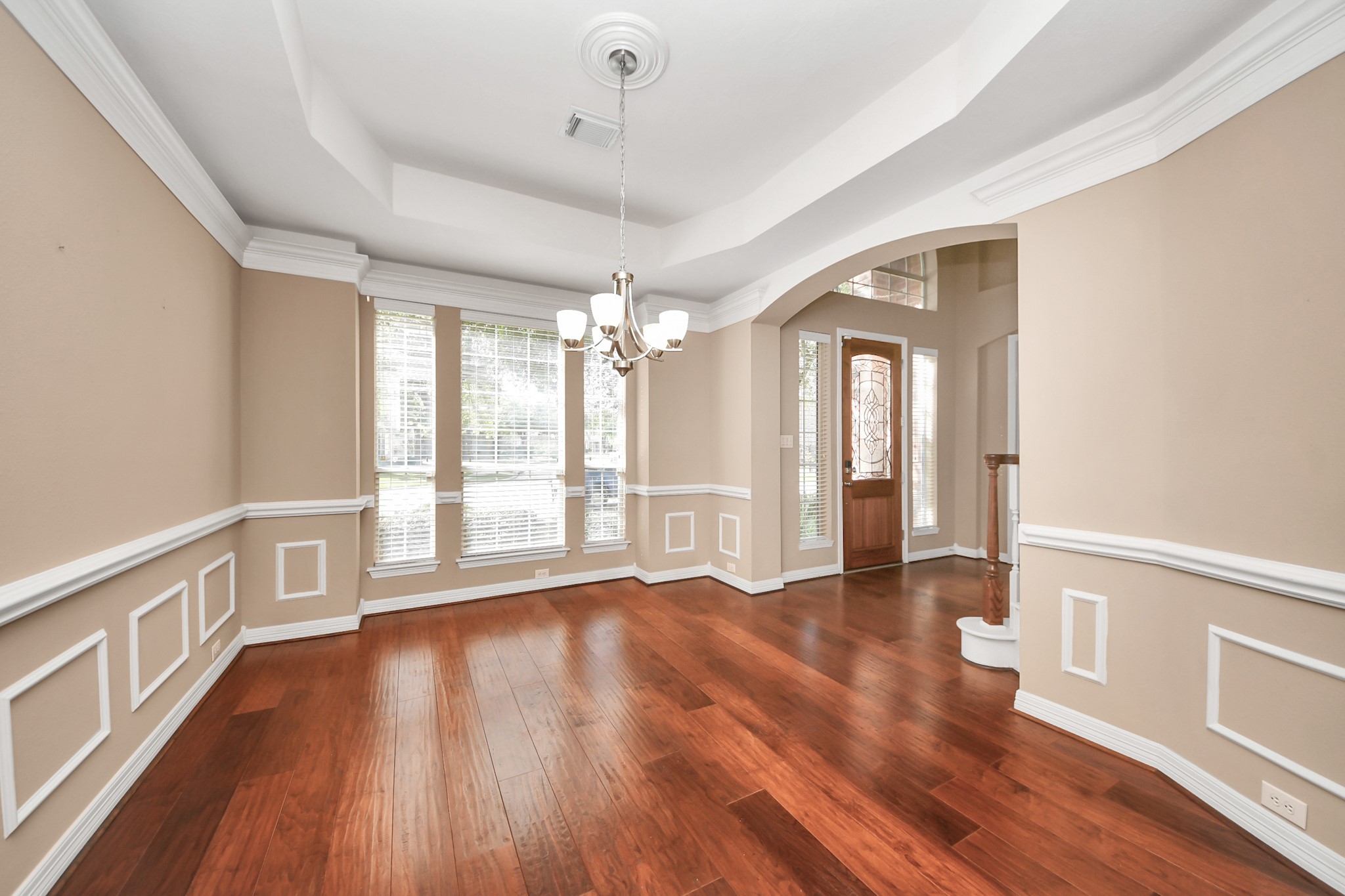 17618 Raven Canyon Lane Houston, TX 77095 - Photo 5 of 45 A spacious formal dining room with crown molding, large windows offering natural light, and beautiful hardwood flooring, providing a welcoming and open space for family and guests.