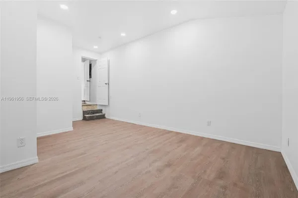 a view of empty room with window and wooden floor