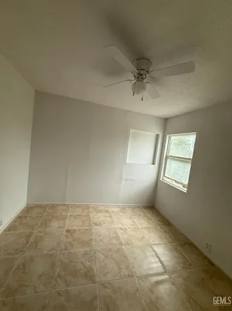 a view of an empty room with window and chandelier fan