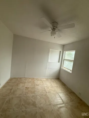 a view of an empty room with window and chandelier fan