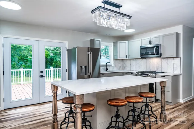 a kitchen with stainless steel appliances a table chairs refrigerator and microwave