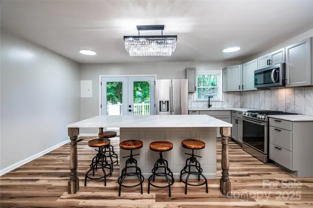 a kitchen with stainless steel appliances a table chairs in it and wooden floors