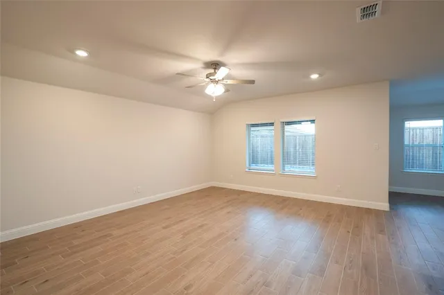 a view of an empty room with a window and wooden floor