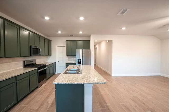 a large kitchen with stainless steel appliances a large counter top a stove a sink and a refrigerator