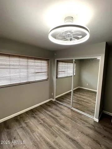 an empty room with wooden floor fan and window