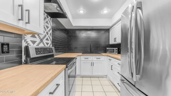 a kitchen with stainless steel appliances kitchen island granite countertop a refrigerator a sink and white cabinets