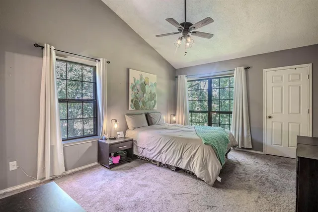 a spacious bedroom with a bed a chandelier and large window