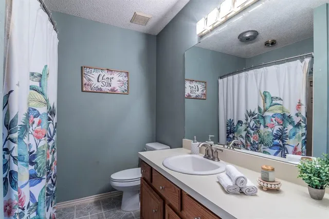 a bathroom with a granite countertop sink mirror vanity and toilet