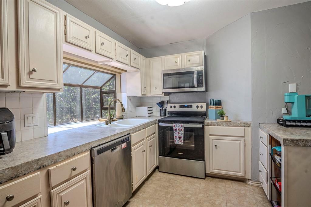 4516 Forestgate Drive Arlington, TX 76017 - Photo 10 of 23 a kitchen with stainless steel appliances granite countertop a stove a sink and a microwave