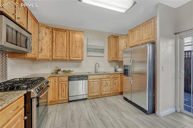 1502 York Road, Unit 102 Colorado Springs, CO 80920 - Photo 7 of 29 Kitchen with a sink, stainless steel appliances, light stone countertops, and wood tiled floor