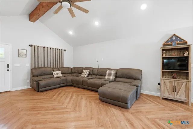 a living room with furniture a flat screen tv and kitchen view