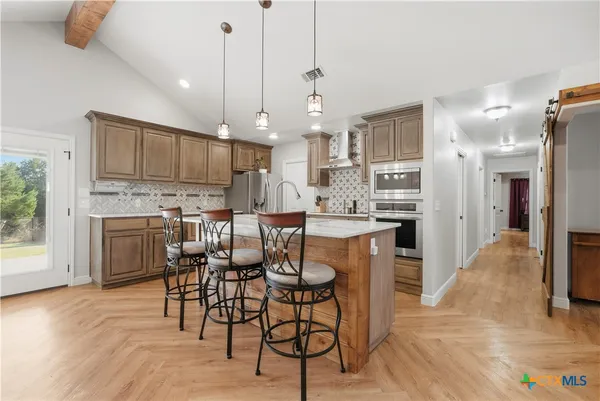 a kitchen with stainless steel appliances kitchen island granite countertop a table chairs and a refrigerator