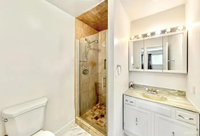 a bathroom with a granite countertop sink toilet and shower