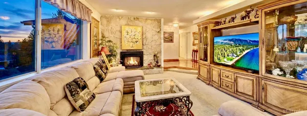 a living room with large furniture a fireplace and a floor to ceiling window