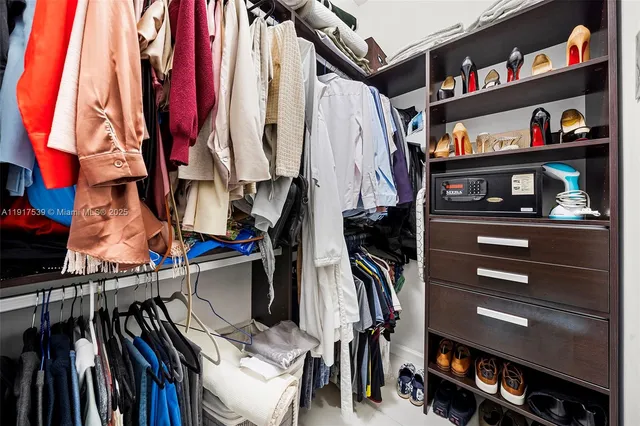 a view of walk in closet with clothes and shoes