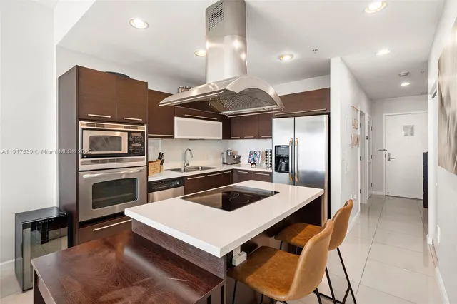 a kitchen with a refrigerator a stove a sink and chairs