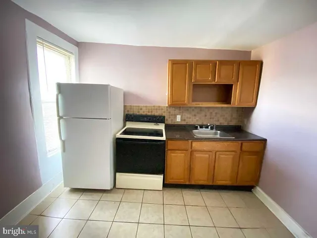 a kitchen with a refrigerator a stove top oven and cabinets