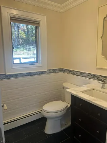 a bathroom with a granite countertop toilet a sink and a window