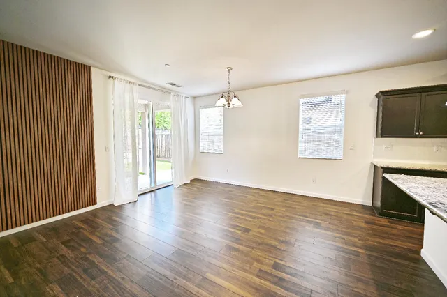 an empty room with wooden floor fireplace and windows