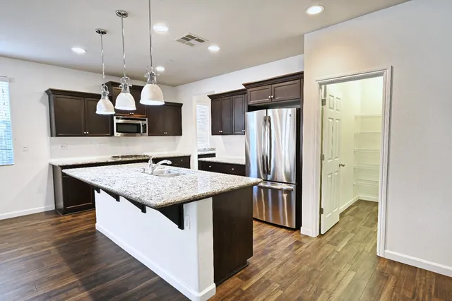 a kitchen with a refrigerator a sink and wooden floor