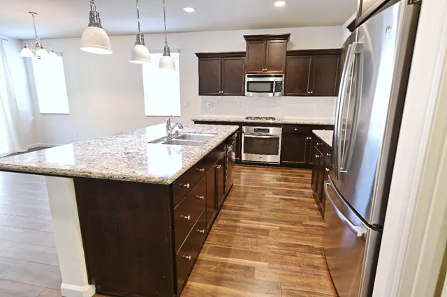a kitchen with kitchen island granite countertop a sink stove and refrigerator