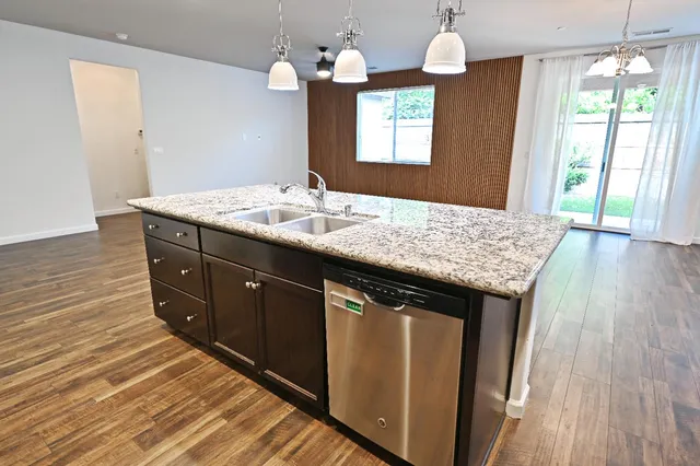 a kitchen with a granite countertop sink window and wooden floor