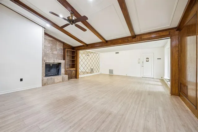 a view of empty room with wooden floor and fireplace
